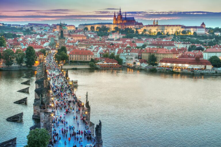 A vibrant view of Charles Bridge leading to Prague Castle at sunset.